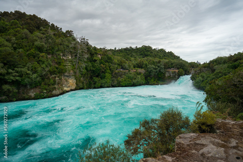 Wasserfall mit t  rkisem Wasser und gr  nen B  umen. Die Huka Falls in Neuseeland.