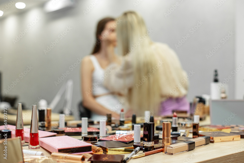 Fototapeta premium Makeup artist makes perfect evening make-up in visage studio. Beauty industry. Lot of cosmetics.