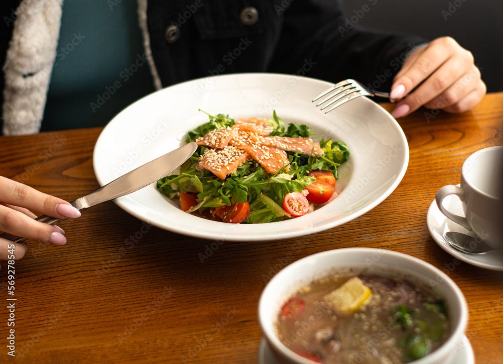 White ceramic plate of fresh salad with salmon, vegetables, tomatoes and arugula with sesame seeds. White ceramic plate of fresh salad with salmon, vegetables, tomatoes and arugula with sesame seeds.