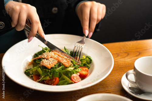 White ceramic plate of fresh salad with salmon, vegetables, tomatoes and arugula with sesame seeds. (ID: 569278574)