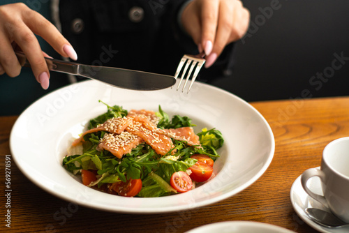 White ceramic plate of fresh salad with salmon, vegetables, tomatoes and arugula with sesame seeds. (ID: 569278591)