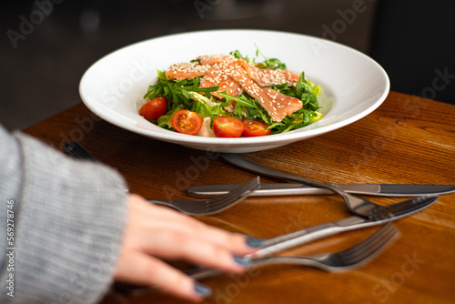 White ceramic plate of fresh salad with salmon, vegetables, tomatoes and arugula with sesame seeds. (ID: 569278746)