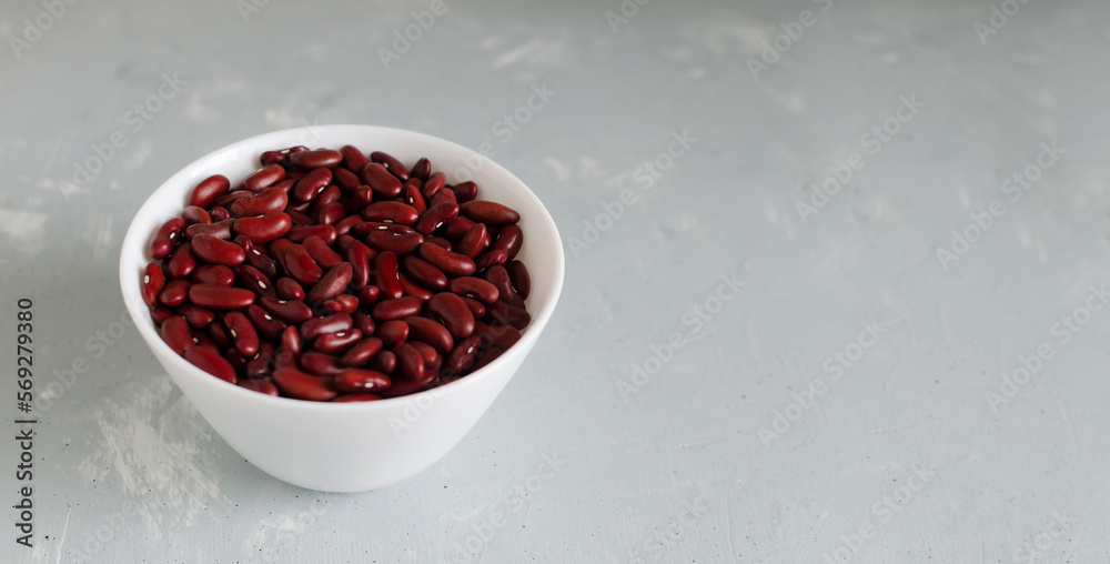 Red beans in a white bowl on a gray background. The concept of vegetarian food. Horizontal orientation. Copy space. Red beans in a white bowl on a gray background. The concept of vegetarian food. Horizontal orientation. Copy space.