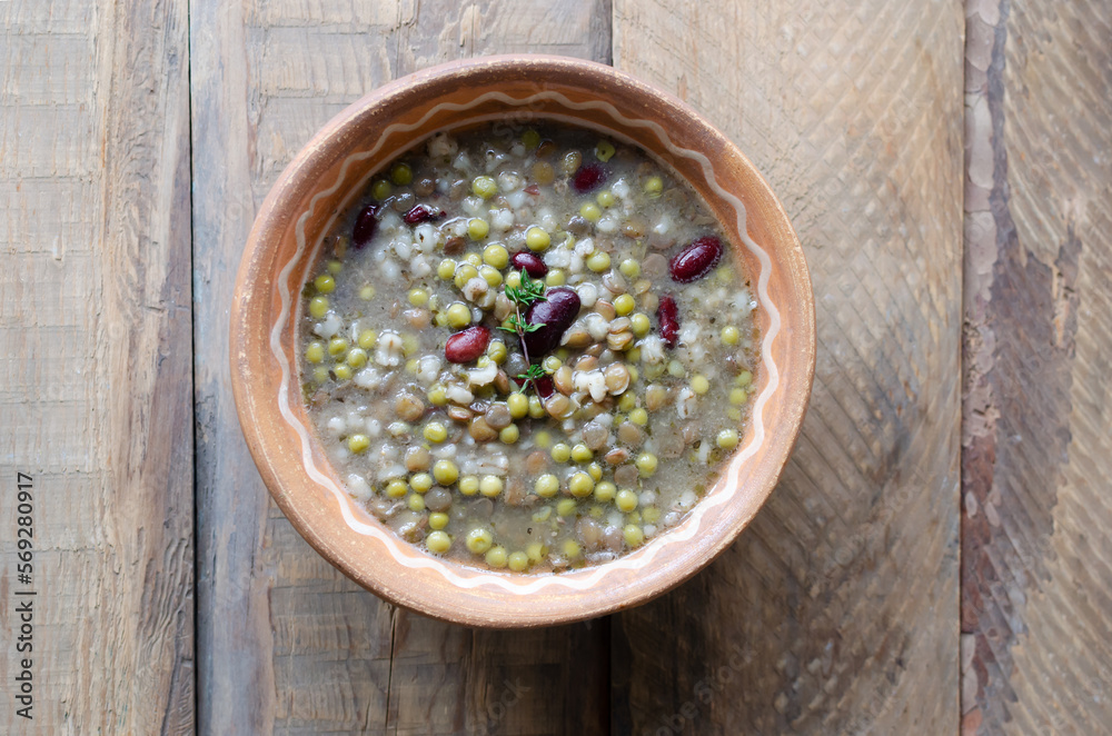Bean soup in a ceramic bowl with a sprig of thyme on a wooden table. A mix of red beans, lentils and peas. The concept of vegetarian food. Rustic style. Horizontal orientation. Copy space. Top view Bean soup in a ceramic bowl with a sprig of thyme on a wooden table. A mix of red beans, lentils and peas. The concept of vegetarian food. Rustic style. Horizontal orientation. Copy space. Top view