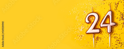 24 years celebration. Greeting banner. Gold candles in the form of number twenty four on yellow background with confetti. photo