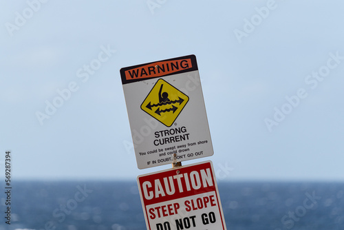 A strong current warning sign with the ocean in the background.