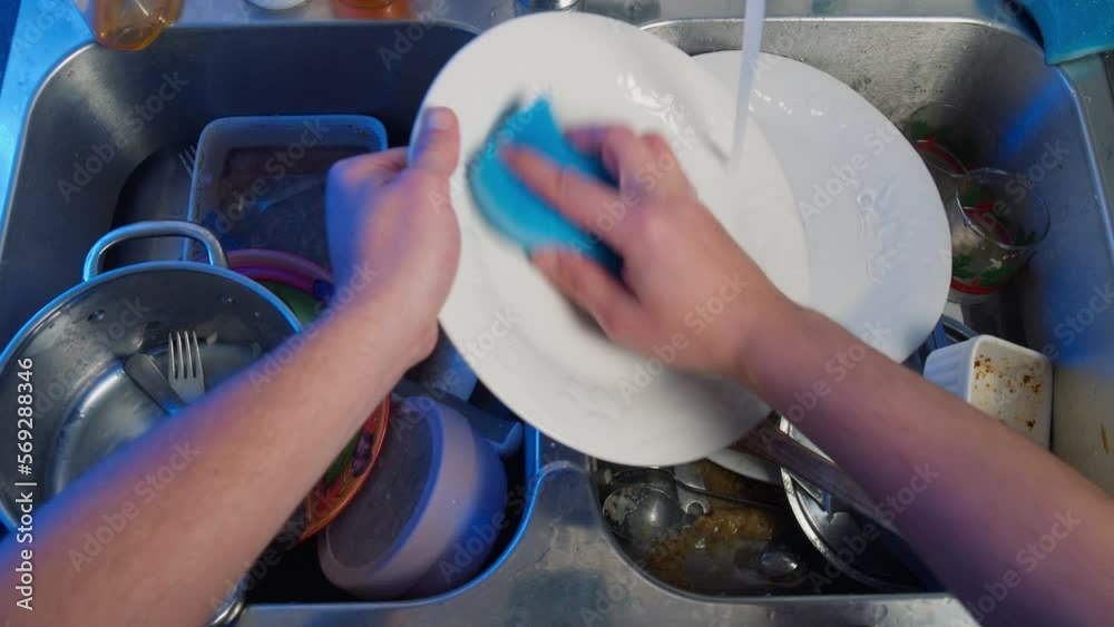 Top view of male hands washing dishes in the kitchen. Pile of dirty