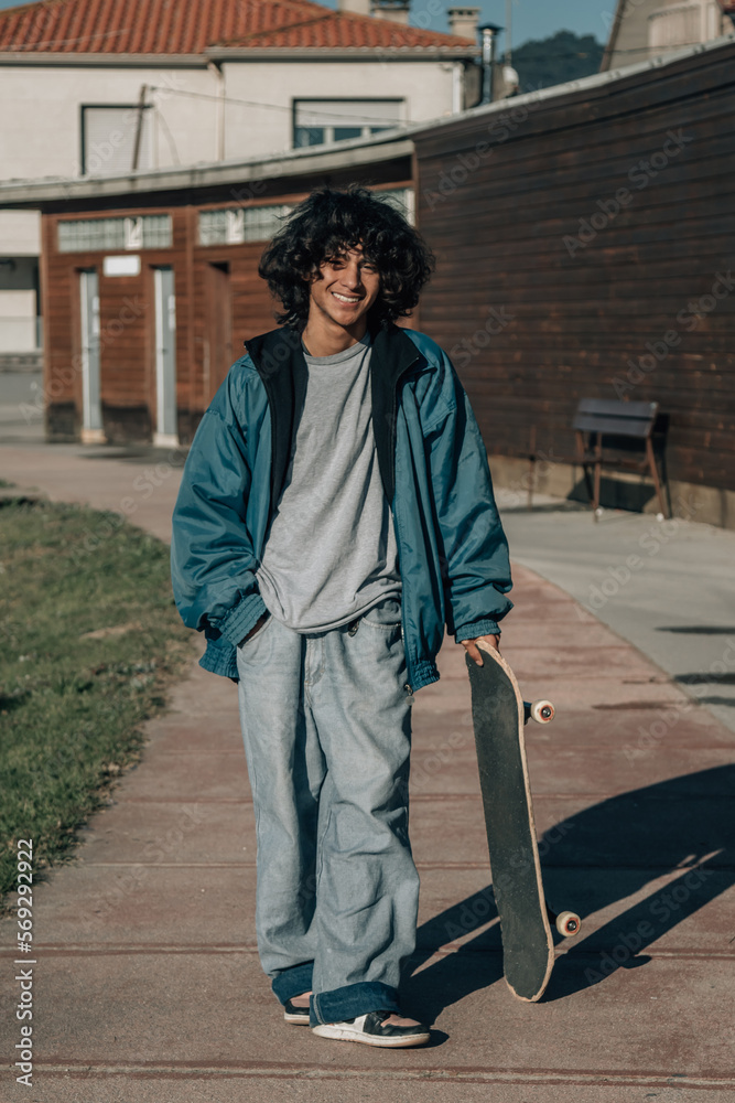 latin teenager with afro hair with skateboard in the street