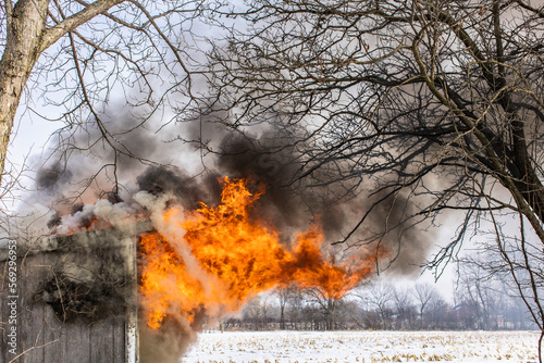 Obraz na plátně Close-up of flames shooting out a small burning shed in the winter