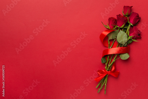 Red roses on color background, top view