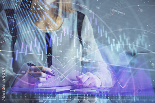 Double exposure of businesswoman hands typing on computer and financial graph hologram drawing. Stock market analysis concept.