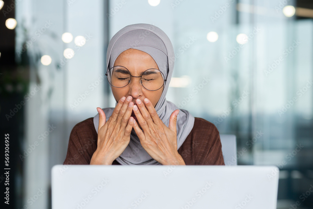 Φωτογραφία Portrait of a young arab woman in hijab and glasses sitting in office at desk with laptop