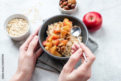 Oatmeal bowl with apple and cinnamon in woman's hands. Concept of vegan diet, clean eating, guilt free dessert Apple Pie Oatmeal for breakfast