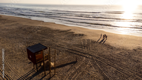 sunset on the beach with a group of friends and a lifeguard house