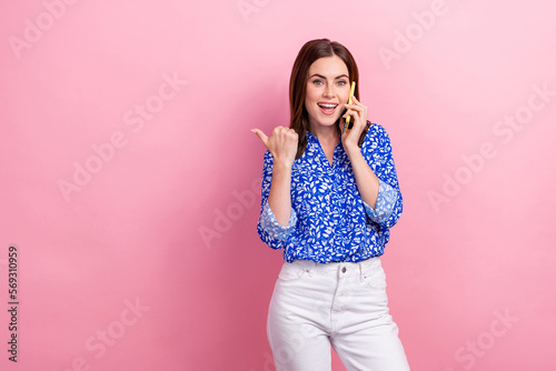 Photo of excited positive lady speak telephone indicate finger empty space isolated on pink color background