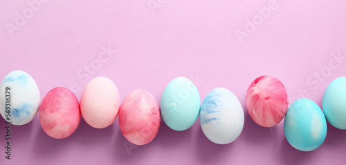 Row of painted Easter eggs on lilac background