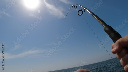 First person view of man's hands reeling in a heavy fish on a spinning reel