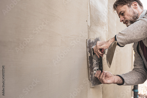 Worker man plastering exterior walls of a house. Renovation of the building facade - construction industry. photo