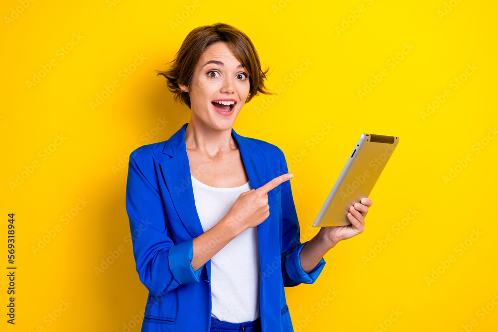 Photo of positive excited lady dressed blue blazer pointing finger modern device isolated yellow color background Photo of positive excited lady dressed blue blazer pointing finger modern device isolated yellow color background