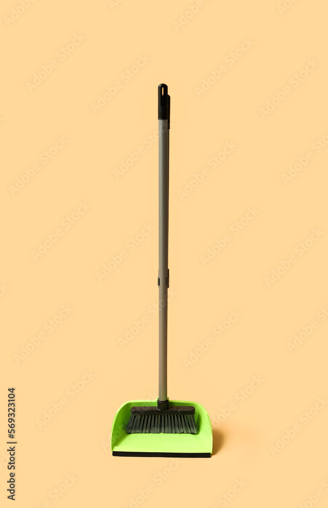 Green dustpan with broom on orange background Green dustpan with broom on orange background