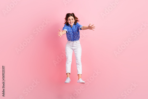 Full length photo of impressed funky woman dressed blue blouse catching big object jumping high isolated pink color background