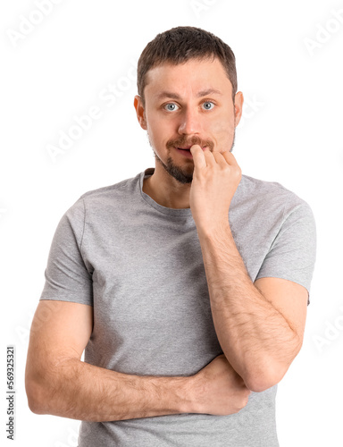 Handsome man in t-shirt biting nails on white background