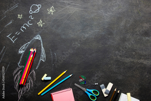 Back to school concept. School supplies on black board background.