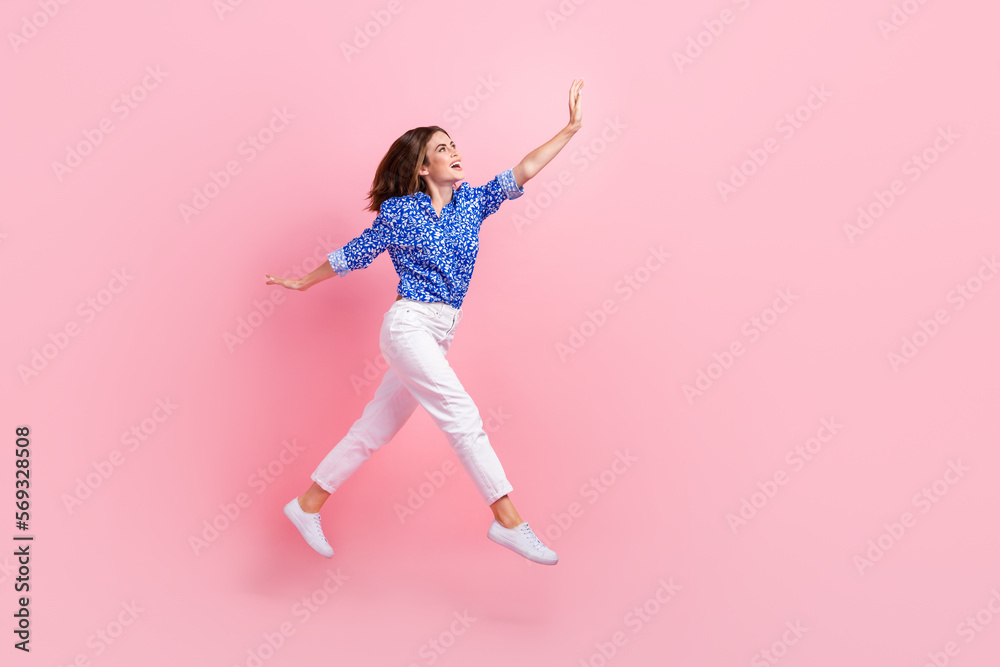 Full length photo of sweet excited woman dressed blue blouse jumping catching arm empty space isolated pink color background