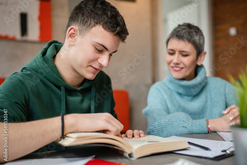 One student teenage caucasian man study learn with help of his tutor professor or mother senior woman at home having private lesson to prepare for exam education concept real people copy space photo