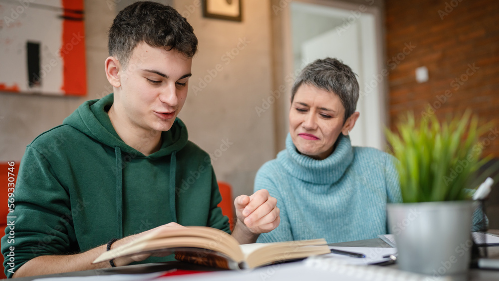 One student teenage caucasian man study learn with help of his tutor professor or mother senior woman at home having private lesson to prepare for exam education concept real people copy space One student teenage caucasian man study learn with help of his tutor professor or mother senior woman at home having private lesson to prepare for exam education concept real people copy space