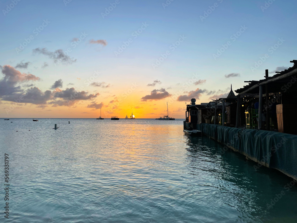 Obraz premium Sailboats on the horizon at sunset, on the Caribbean sea, off the coast of Aruba