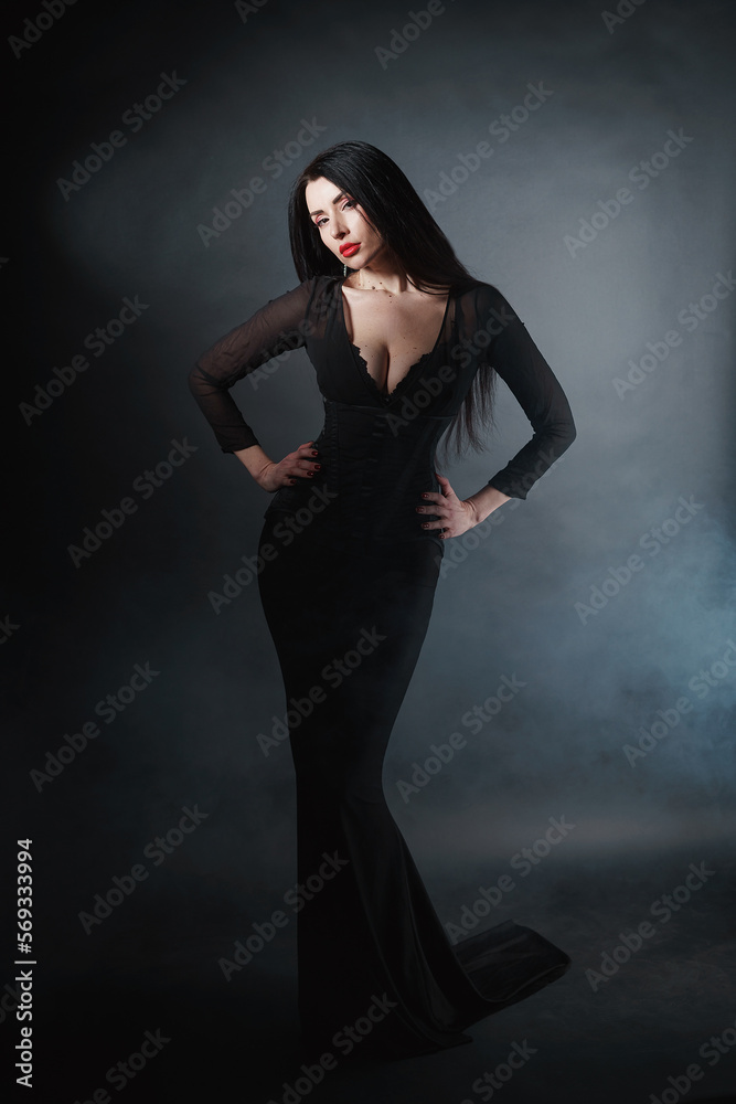 Beautiful sexy girl with a mystical look in a black bodycon dress on a black background