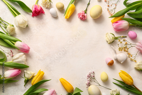 Frame made of beautiful flowers and Easter eggs on light background