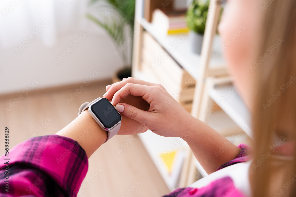 Unrecognizable woman checking smartwatch indoors