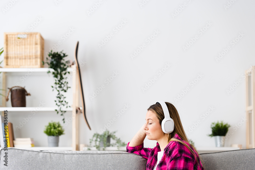 Young blonde woman listening relaxing music at home with copy space