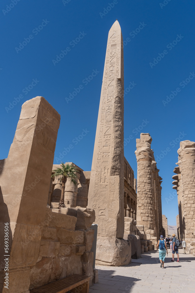 Karnak temple obelisk in Luxor on a sunny day with tourists.
