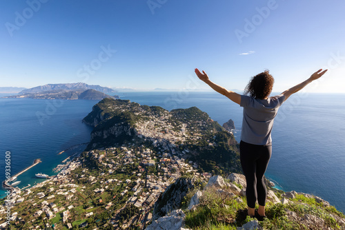 Adventure Woman Hiking on mountain at Touristic Town, Capri Island, in Bay of Naples, Italy. Sunny Blue Sky.