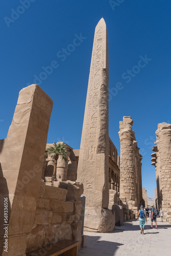 Karnak temple obelisk in Luxor on a sunny day with tourists.