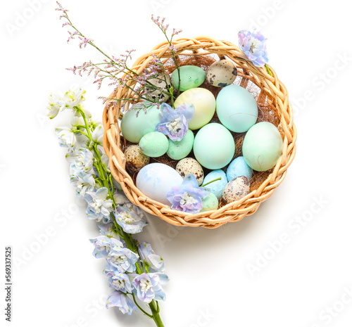 Basket with beautiful Easter eggs and flowers on white background © Pixel-Shot