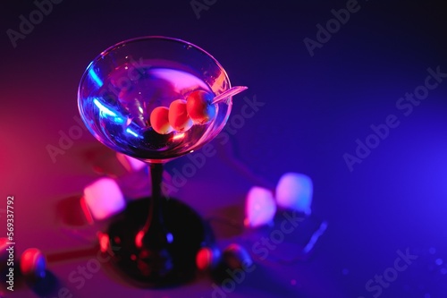 Martini glass and olives on a black background with neon lights