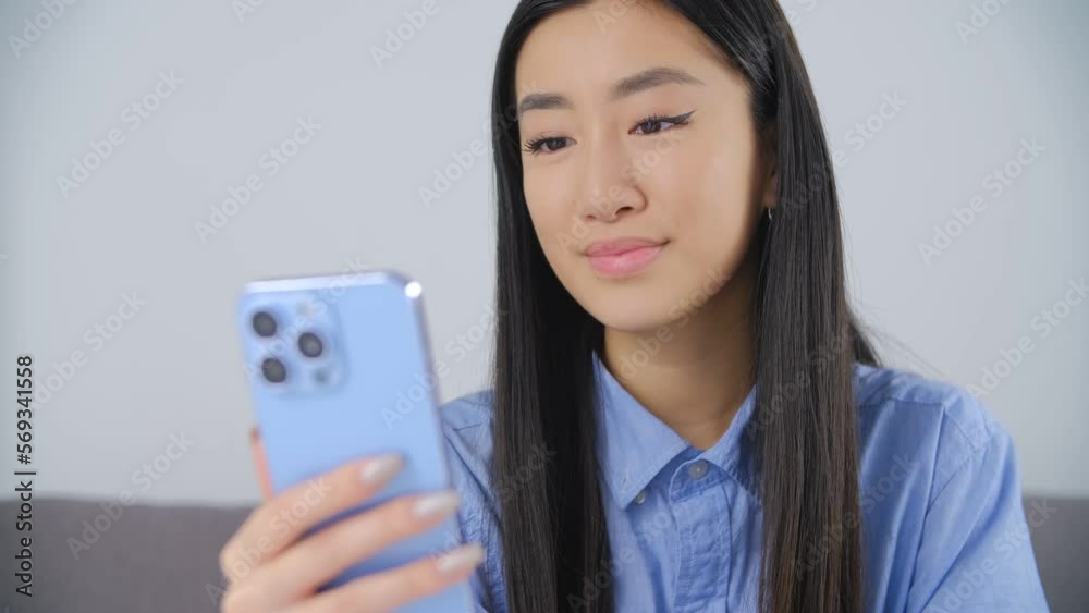 Beautiful Vietnamese girl typing a message on a smart phone. Close up video of pretty BIPOC female communicating online with modern blue cell phone Beautiful Vietnamese girl typing a message on a smart phone. Close up video of pretty BIPOC female communicating online with modern blue cell phone