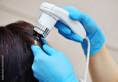 doctor cosmetologist dermatologist diagnoses the condition of the patient's hair using a special device - a trichoscope. photo