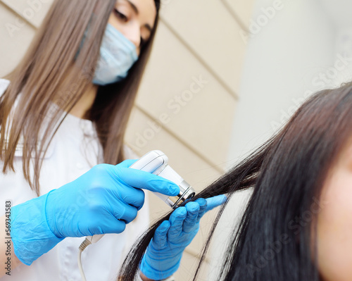 doctor cosmetologist dermatologist diagnoses the condition of the patient's hair using a special device - a trichoscope. photo