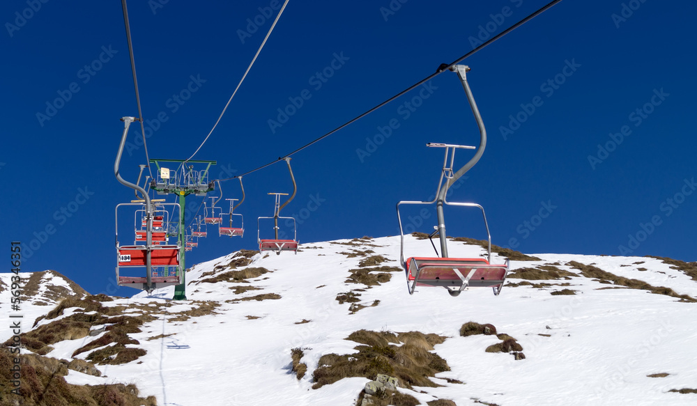 Alps in the background, chair lift in the foreground the towering mountains are covered with fresh white snow against turquoise sky Alps in the background, chair lift in the foreground the towering mountains are covered with fresh white snow against turquoise sky