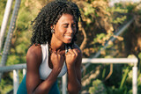 retrato de bella mujer negra sonriendo después de correr y hacer ejercicios en un día de sol, en la ciudad, al atardecer.