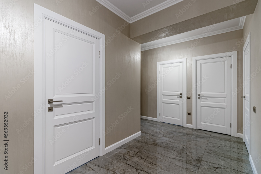 Fototapeta premium Corridor with white walls and doors in an apartment with a marble floor