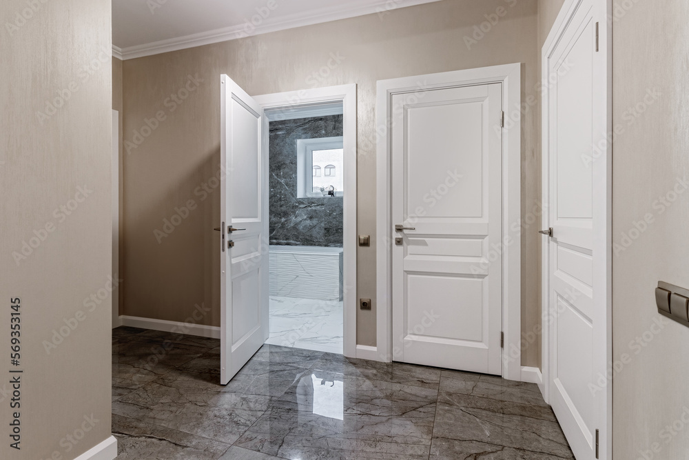 Corridor with white walls and doors in an apartment with a marble floor Corridor with white walls and doors in an apartment with a marble floor