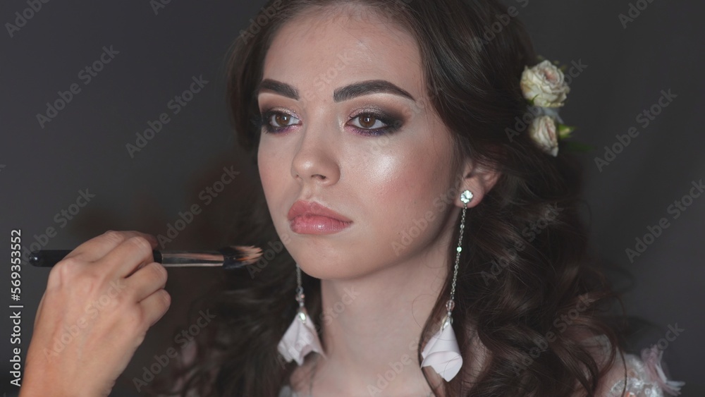 Obraz premium Girl make-up artist applies powder on the face of the model.