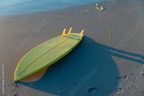 High angle view of yellow surfboard on sandy beach at shore during sunset