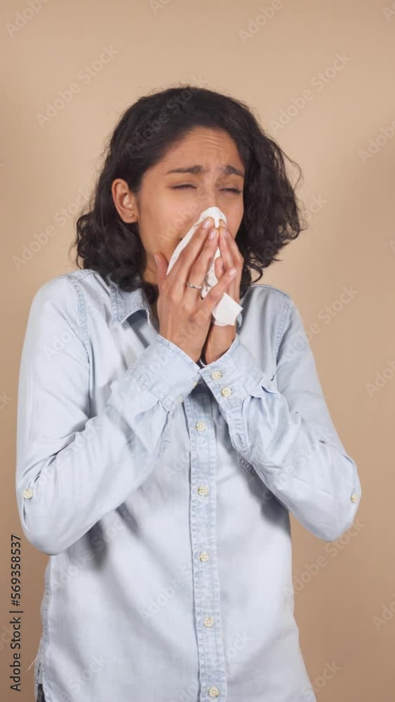 vertical video of young latina woman, sneezing heavily, with flu. vertical video of young latina woman, sneezing heavily, with flu.